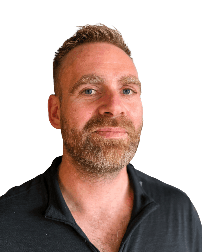 A man with short brown hair, a beard, and blue eyes looks ahead.